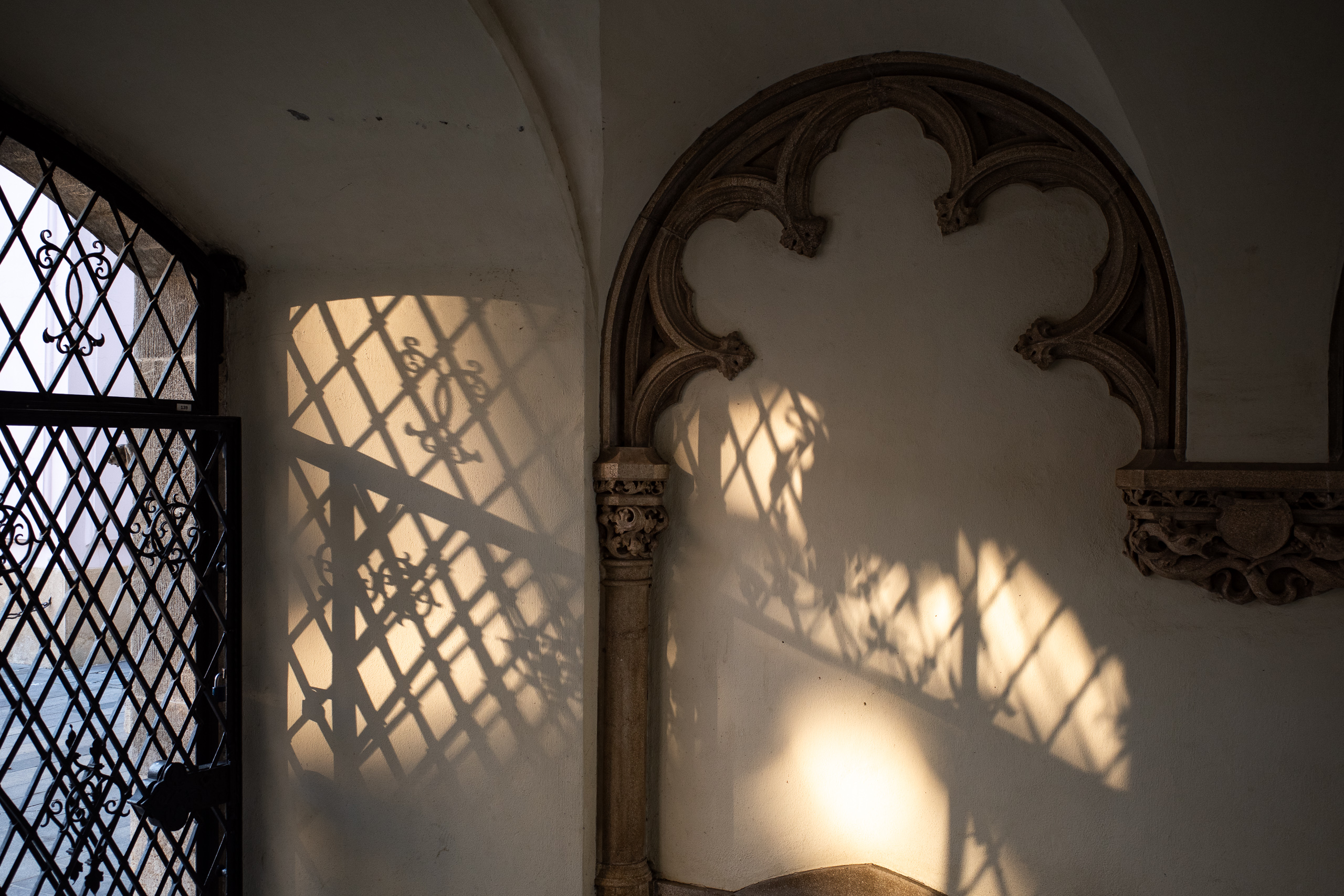 Gitterschatten auf der Wand neben dem gotischen Maßwerk